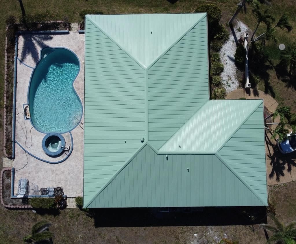 Overhead view of a green standing seam metal roof next to a pool
